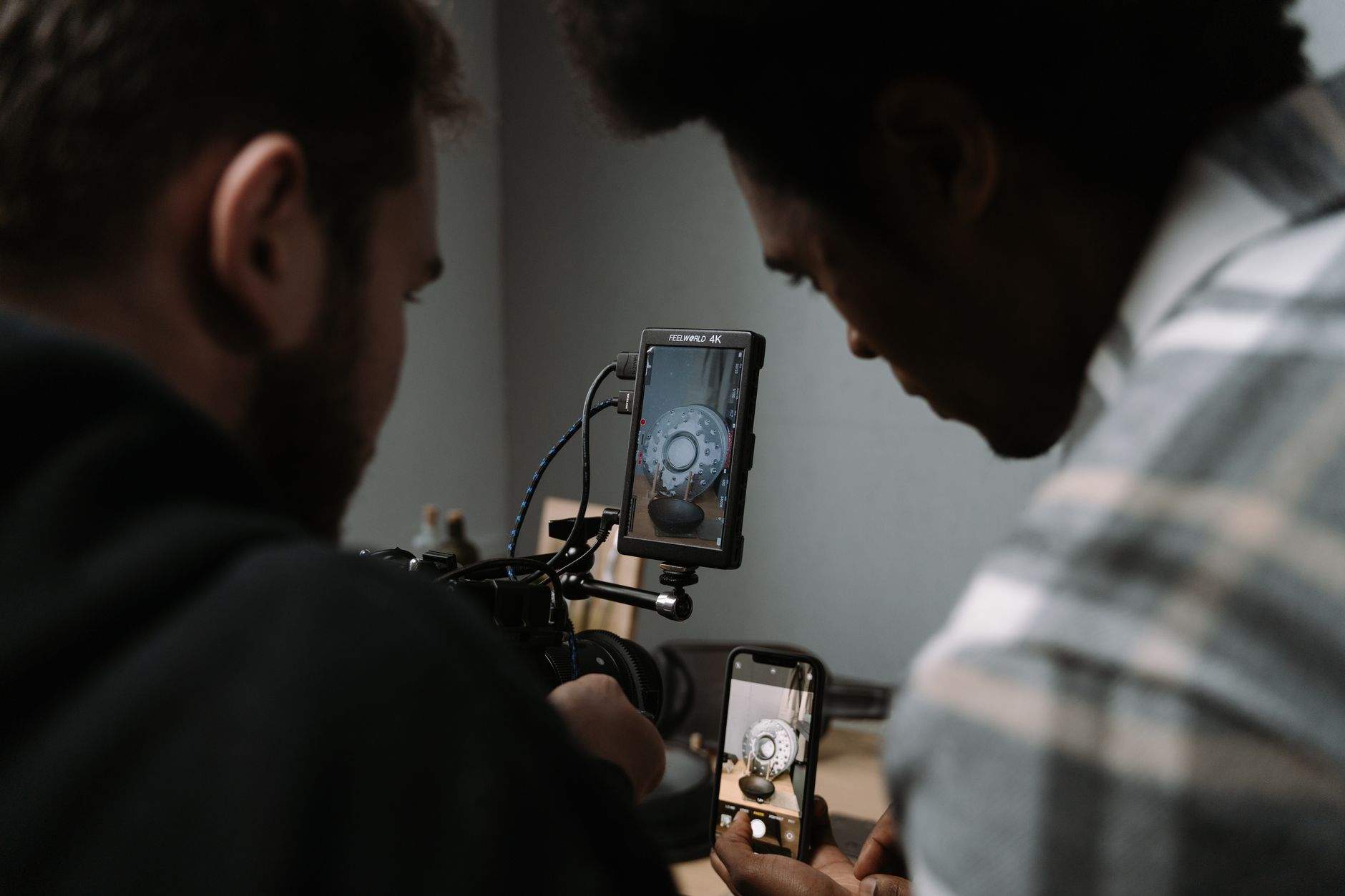 Deux hommes penchés sur un écran de contrôle et un smartphone pour relire une prise de vue dans un studio